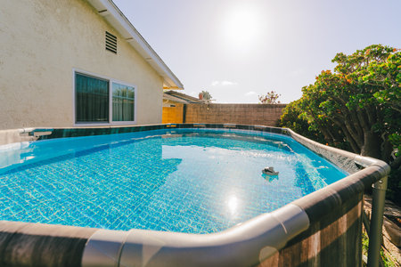 Above-ground pool in a backyard surrounded by greenery.