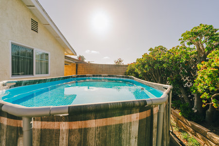 Backyard with an above-ground pool and lush green plants on a sunny day.の写真素材