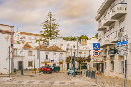 Tavira, Portugal, January 8, 2024. Street view in Tavira, Portugal, with cobblestone roads, a mix of traditional and modern buildings, and various street signs.のeditorial素材