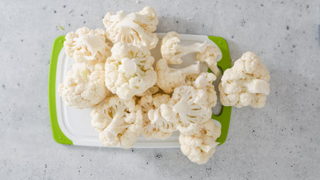 Cauliflower florets close-up on cutting board on grey stone background, flat layの写真素材