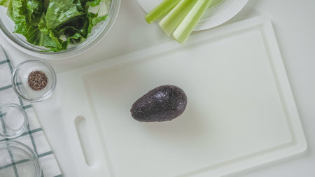 Avocado on white cutting board. Green salad recipe, ingredients on white background, flat layの写真素材