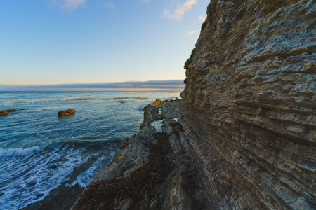 Beautiful seascape. Blue sea, and rocky cliffs on the beach with cloudy sky in the background