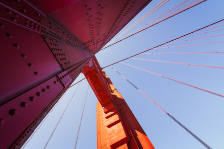 Looking up at the towering structure of the Golden Gate Bridge against the sky.の写真素材