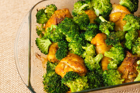 Baked chicken drumstickes and broccoli in a glass baking dish close-up on a kitchen table, just from the oven, delicious dinnerの写真素材