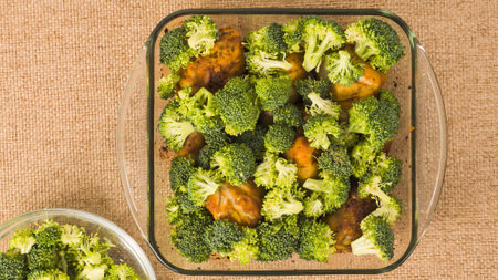 Baked chicken drumsticks and broccoli recipe. Baking dish close-up on a kitchen table, flat layの写真素材