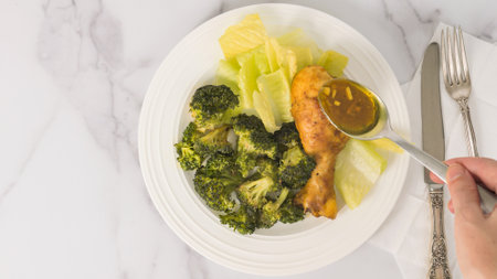 The chef topping baked chicken drumstick with a garlic butter sauce. Meal on a plate, close-up view from above, marble background with a copy spaceの写真素材