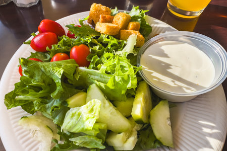 Healthy salad served with crisp vegetables, croutons, and creamy dressing.の写真素材