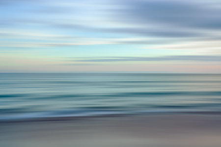 Dynamic lines of blue and orange blur together in this abstract depiction of the ocean at sunsetの写真素材