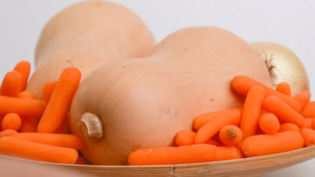 Butternut squash soup recipe. Raw vegetables close-up on the kitchen table. Butternut squash, carrot, onion, and garlic close-up on a wooden plateの写真素材