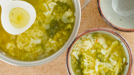 Serving soup. Cauliflower broccoli soup in a bowl close-up on a table on a rustic background, view from aboveの写真素材