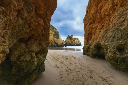 Breathtaking coastal scene with rugged cliffs, natural arches, and caves set against a dynamic cloudy skyの写真素材