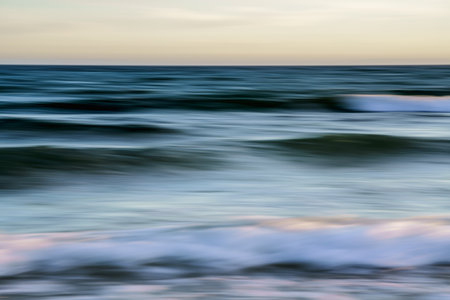 Blurred motion of ocean waves at dusk creates a dreamy seascape.