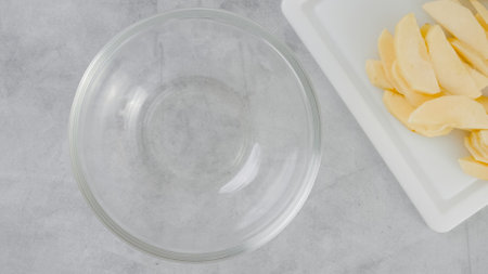 Apple cake recipe. Sliced apples on a cutting board, and a glass bowl close-up on a kitchen table, flat layの写真素材