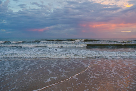 Calm ocean scene as dusk colors the clouds in gentle pastels.の写真素材