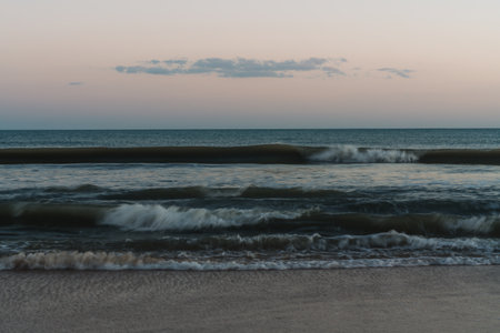 Smooth, blurred waves reflecting dusk light in serene tones.の写真素材