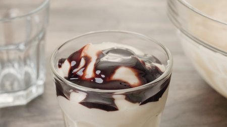 White chocolate vanilla bean pudding in a glass on a wooden table. Topping vanilla pudding with dark chocolate sauce.の写真素材
