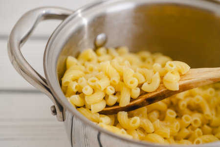 Cooked pasta in a pot. Elbows pasta in a cooking pot close-up on a tableの写真素材
