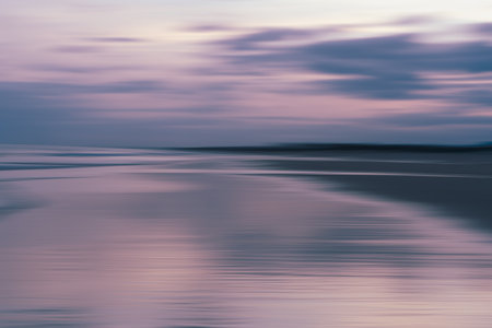 Gentle waves rolling toward the shore under a pastel-colored sky, abstract seaの写真素材