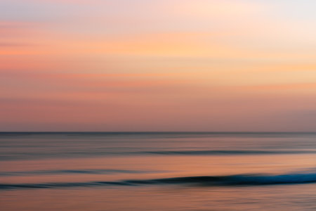 Serene horizon with gentle waves under a warm, fading sky.の写真素材