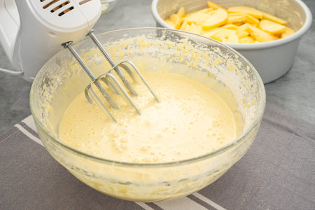 Cake batter in a glass bowl close-up on a kitchen table. Apple cake recipeの写真素材