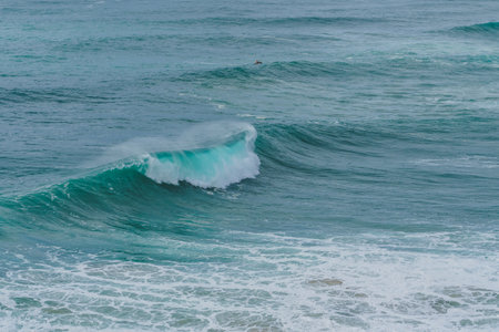 Turquoise waves cresting and frothing in a rhythmic pattern at Nazares renowned surf spot.の写真素材