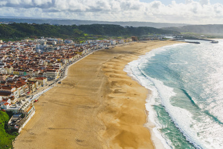 Cloud shadows drift over Nazare, where the town meets the tumbling waves of the Atlantic. Portugalの写真素材