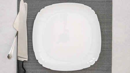 White plate on a grey tablecloth close-up on a table, flat lay with a copy spaceの写真素材