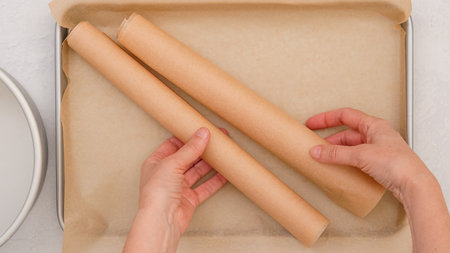Close-up moment of the baking process, hands skillfully place parchment paper onto a baking pan, exuding a sense of focused preparation.の写真素材