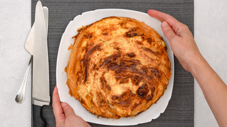Chef presents a freshly baked phyllo dough pie with a golden crust, showcasing a decadent cream cheese filling, flat layの写真素材