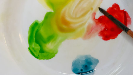 Watercolor palette with yellow, green, and red paint and a brush on white.の写真素材