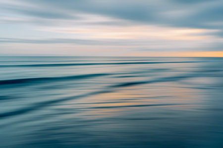 Ethereal waves flow in a blurred dance of blues and oranges in a serene seascapeの写真素材