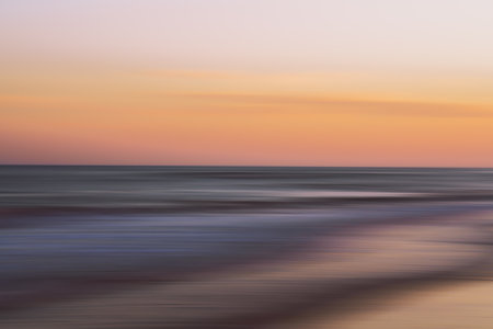 Gentle waves and pastel skies create a peaceful, abstract seascape.の写真素材