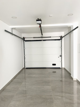 Modern garage with a white automatic door and polished gray tiled flooring.の写真素材