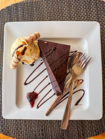 Rich chocolate cake served with vanilla ice cream and decorative wafer rolls.の写真素材