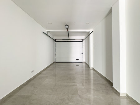 Minimalist garage featuring clean white walls, a motorized door, and ample space.の写真素材