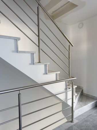 Elegant marble staircase with a sleek stainless steel railing in a modern interior.の写真素材