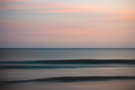 Ocean and pink colored cloudy sky, abstract seascape background, motion blur, sunset.の写真素材