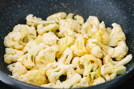 Cauliflower florets sautÃ©ing in a black non-stick pan with seasoning.の写真素材