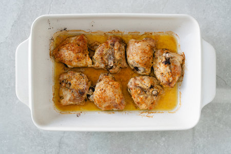 Freshly baked chicken thighs out of the oven, tender and juicy in their own broth.の写真素材