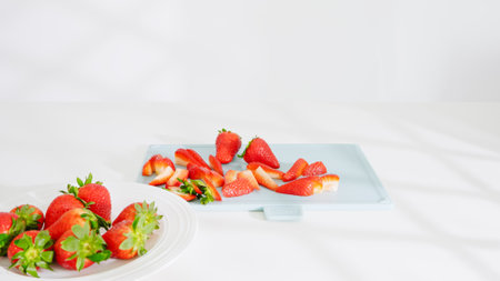 Sliced strawberries placed neatly on a blue cutting board under soft daylight.