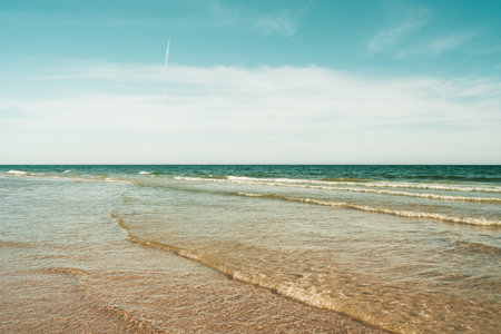 Peaceful beach with soft waves and blue sky.の写真素材