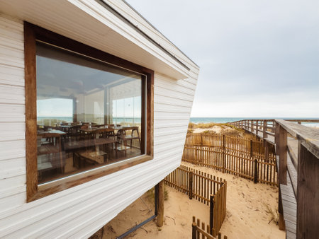 Beachfront restaurant on stilts overlooks sandy dunes and ocean views.の写真素材