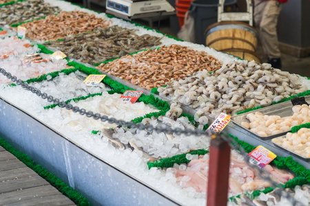Assorted seafood including shrimp, fish, and scallops displayed on ice in a seafood market.の写真素材