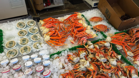 Fresh crab legs, whole crabs, and containers of lump crabmeat are displayed on ice at a seafood vendor counter.の写真素材