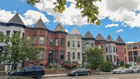 Washington D.C., USA, May 24, 2025. A row of turreted brick and painted rowhouses sits under a bright blue sky with scattered clouds.のeditorial素材