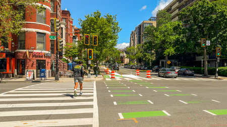 Washington D.C., May 24, 2025. A jogger moves through a crosswalk at a green-lit intersection...