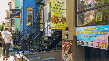 Washington D.C., May 24, 2025. Colorful signs for Abuare Bar and Restaurant advertise Ethiopian and Eritrean vegan dishes on a lively city block.のeditorial素材