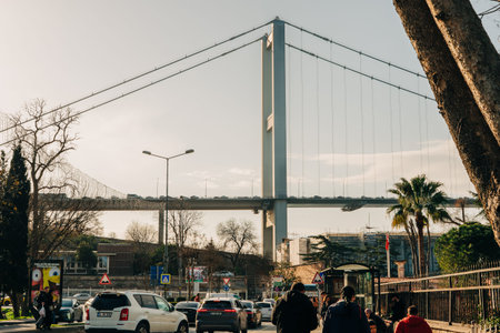 Istanbul, Turkey, January 7, 2025. Busy city street with pedestrians and cars passes under the Bosphorus Bridge, its towering suspension cables rising above the urban landscape.のeditorial素材