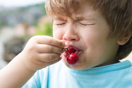 Sour cherry, sour taste. Baby boy first tries cherry. Emotional child. Healthy food. Apetite....