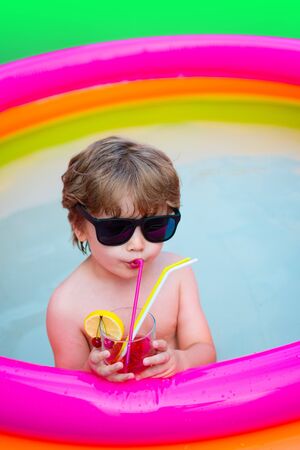 Summer cocktail. Vacation. Summer holidays. The child drinks colorful cocktail in sunglasses. Enjoyment Resort. Cocktail pool for relaxing. Happy time. Happy hours. Luxury life. Delicious heat drink.の写真素材
